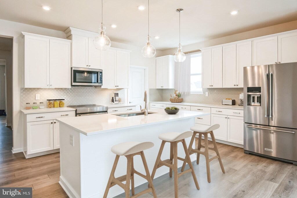 24013 Bark Wood Ct, Lewes, DE 19958 - kitchen with stainless steel appliances, recessed lighting, light wood-type flooring, decorative backsplash, and a center island with sink