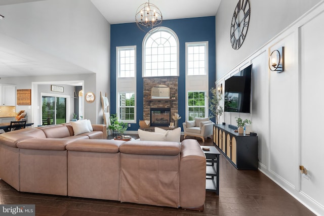 815 Summersweet Ct, Huntingtown, MD 20639 - living area featuring a chandelier, dark wood-type flooring, a towering ceiling, plenty of natural light, and a stone fireplace