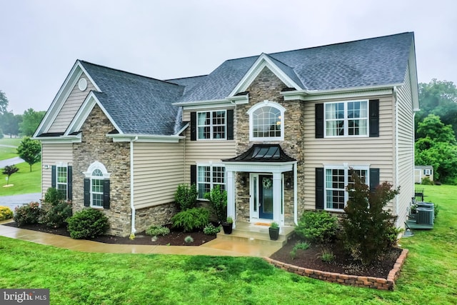 815 Summersweet Ct, Huntingtown, MD 20639 - georgian-style home with stone siding, a front lawn, a shingled roof, and cooling unit