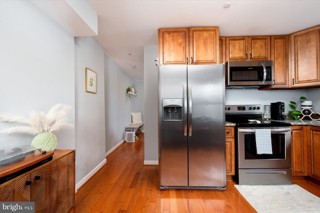 1005 Madison Ct, Annapolis, MD 21403 - kitchen with stainless steel appliances, brown cabinetry, light wood-type flooring, and baseboards