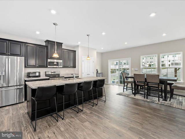 107 Lookout Way, Fredericksburg, VA 22405 - kitchen featuring stainless steel appliances, a center island with sink, a breakfast bar, wood finished floors, and light stone counters