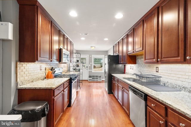 3234 Odonnell St, Baltimore, MD 21224 - kitchen featuring appliances with stainless steel finishes, a sink, tasteful backsplash, light wood-style flooring, and light stone countertops