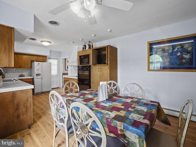 4326 Ranger Ave, Temple Hills, MD 20748 - dining space with light wood-style flooring, a ceiling fan, and a baseboard radiator