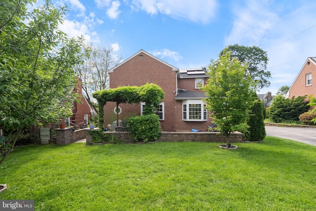 915 Edgewood Dr, Springfield, PA 19064 - back of house featuring a lawn, brick siding, and solar panels