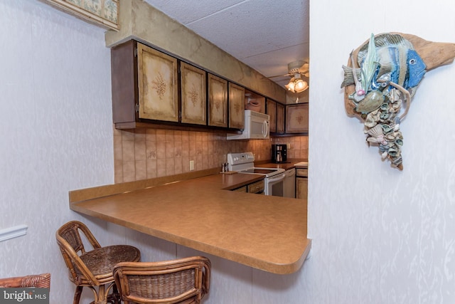 10300 Coastal Hwy Unit 1905, Ocean City, MD 21842 - kitchen featuring white appliances, ceiling fan, decorative backsplash, a textured ceiling, and a kitchen bar