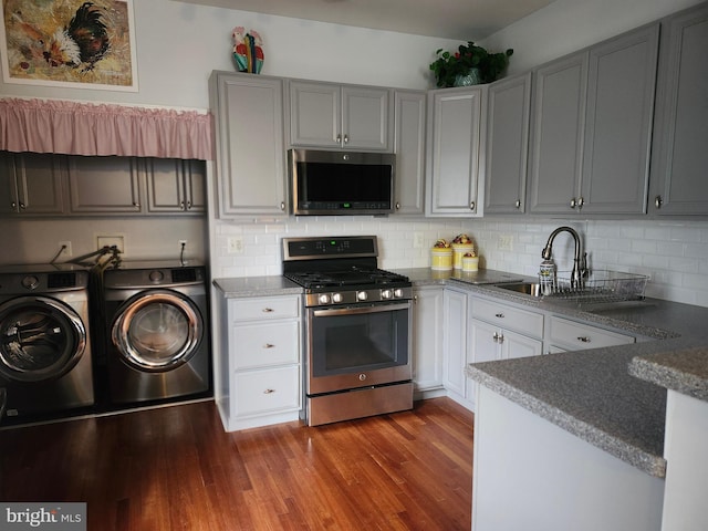 45 Freedom Ln, Bensalem, PA 19020 - kitchen featuring appliances with stainless steel finishes, independent washer and dryer, a sink, tasteful backsplash, and dark wood finished floors