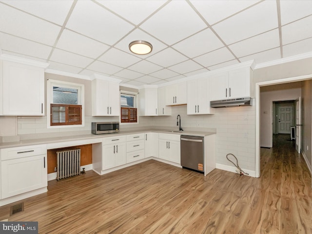 1707 Hall Ave, Baltimore, MD 21227 - kitchen with appliances with stainless steel finishes, radiator, under cabinet range hood, ornamental molding, and white cabinets