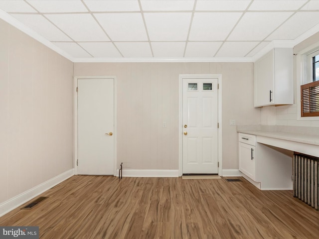 1707 Hall Ave, Baltimore, MD 21227 - kitchen with light wood-type flooring, white cabinetry, light countertops, crown molding, and wood walls