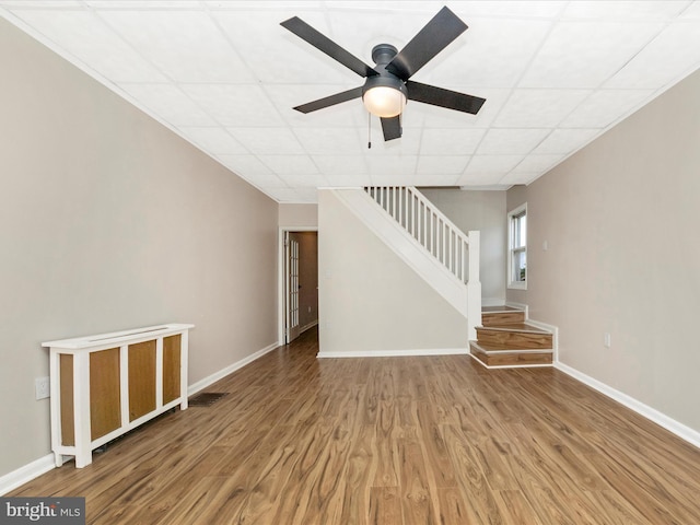 1707 Hall Ave, Baltimore, MD 21227 - unfurnished living room featuring stairs, wood finished floors, a drop ceiling, and ceiling fan