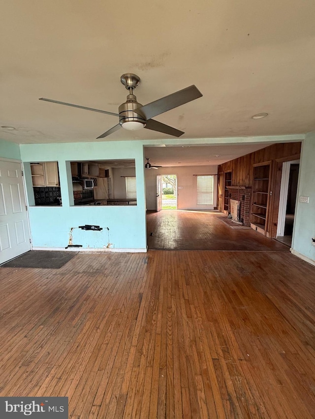 5227 Al Jones Dr, Shady Side, MD 20764 - unfurnished living room with hardwood / wood-style flooring, a ceiling fan, and wood walls
