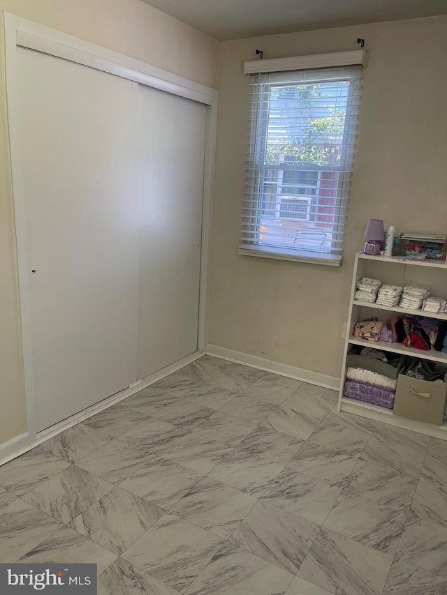 1604 Manning Rd, Glen Burnie, MD 21061 - unfurnished bedroom featuring marble look tiles, a closet, and baseboards