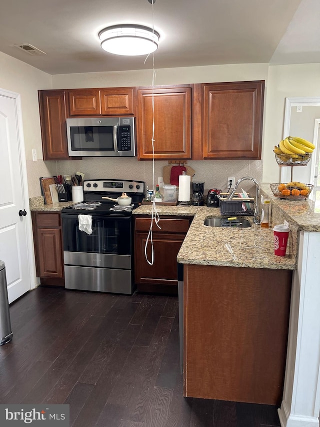 1604 Manning Rd, Glen Burnie, MD 21061 - kitchen with stainless steel appliances, a sink, dark wood-style flooring, light stone counters, and brown cabinets