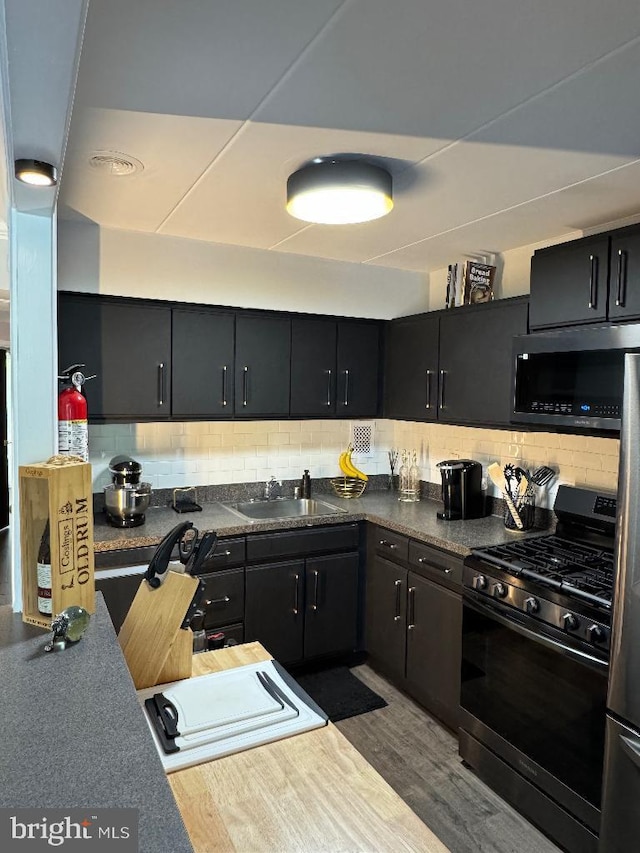2622 Wagon Dr Unit 319, Alexandria, VA 22303 - kitchen featuring stainless steel gas range oven, a sink, backsplash, wood finished floors, and dark cabinets