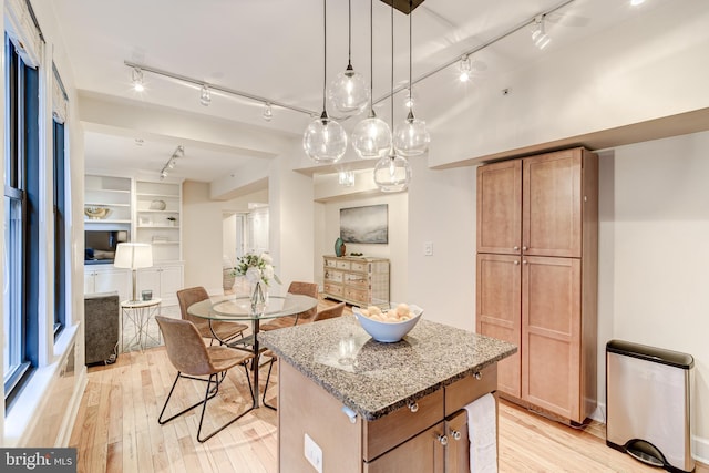 1858 California St NW Unit 20, Washington, DC 20009 - kitchen with rail lighting, a center island, light wood-style floors, light stone counters, and pendant lighting