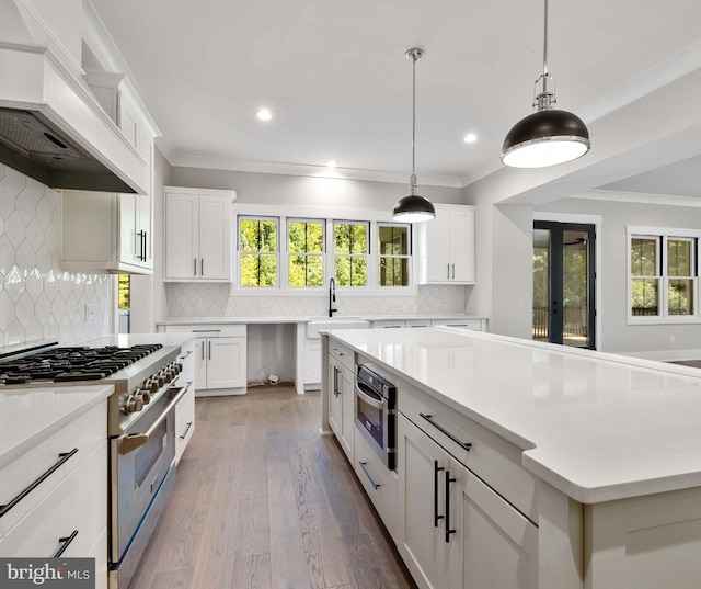 3908 Baltimore St, Baltimore, MD 21227 - kitchen featuring high end stainless steel range oven, custom range hood, crown molding, healthy amount of natural light, and backsplash