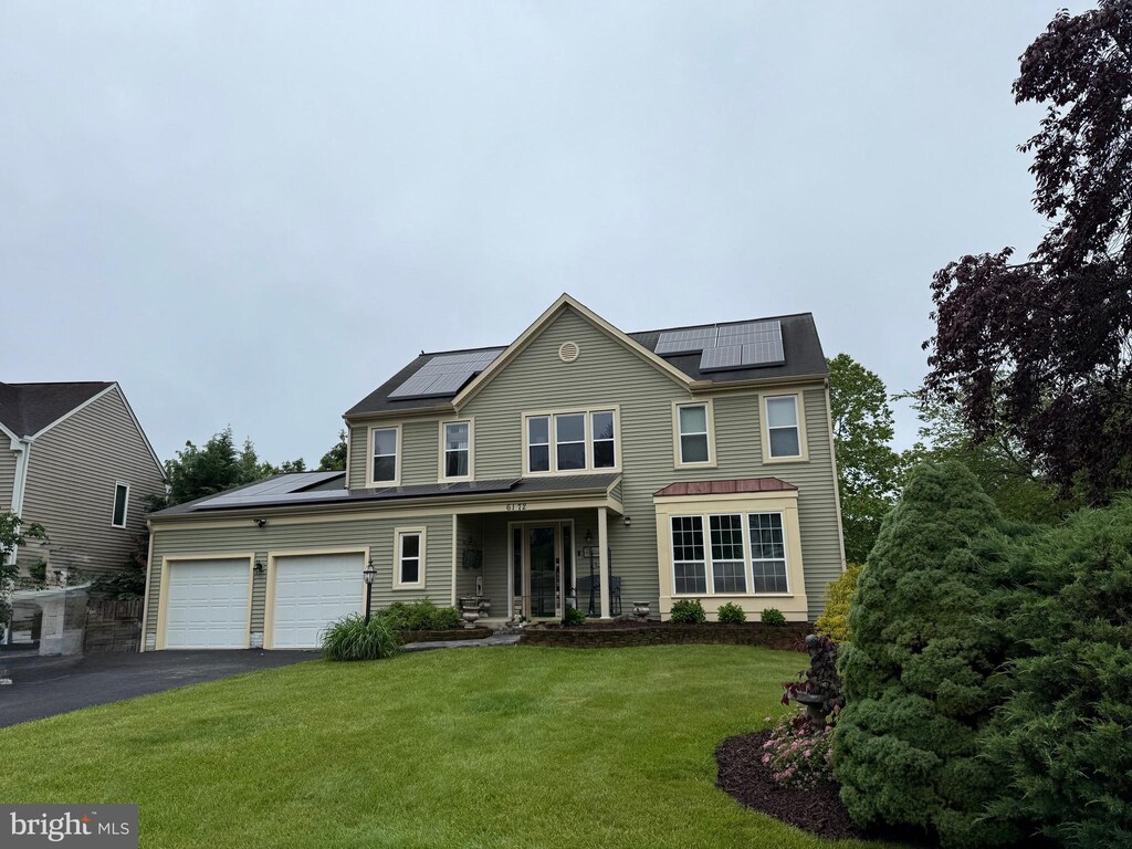 6172 Mississippi Ln, New Market, MD 21774 - back of house with solar panels, an attached garage, asphalt driveway, a lawn, and covered porch