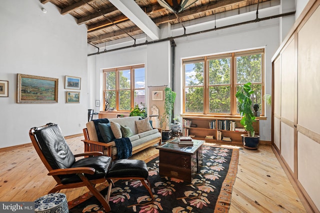 3132 E Thompson St Unit 2C, Philadelphia, PA 19134 - living room featuring wood ceiling with exposed beams, a towering ceiling, hardwood / wood-style flooring, and baseboards