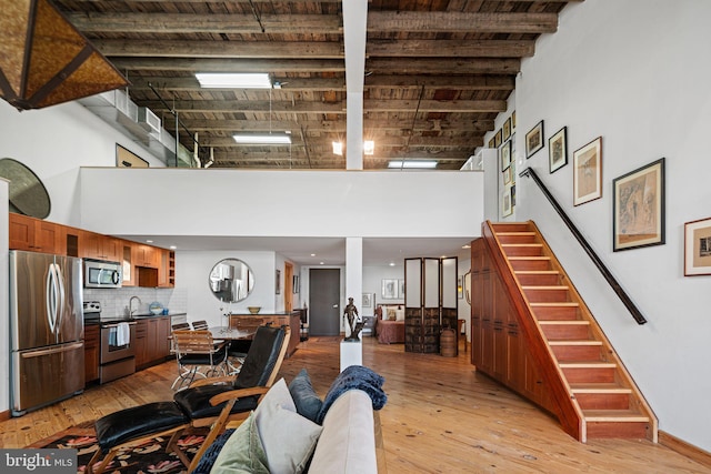 3132 E Thompson St Unit 2C, Philadelphia, PA 19134 - living room featuring a high ceiling, stairs, light wood finished floors, and baseboards