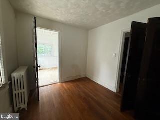 813 Sheridan St NW, Washington, DC 20011 - empty room with radiator heating unit, wood finished floors, baseboards, and a textured ceiling