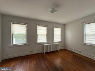 813 Sheridan St NW, Washington, DC 20011 - spare room featuring radiator heating unit, healthy amount of natural light, wood finished floors, and baseboards