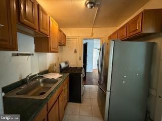 813 Sheridan St NW, Washington, DC 20011 - kitchen featuring stainless steel appliances, a sink, dark countertops, brown cabinetry, and light tile patterned flooring