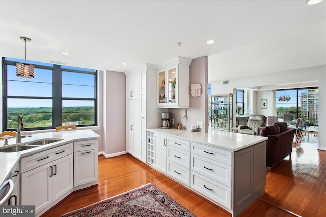 1830 Fountain Dr Unit 1107, Reston, VA 20190 - kitchen featuring a peninsula, light wood-style flooring, glass insert cabinets, white cabinetry, and pendant lighting