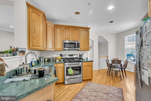 10079 Orland Stone Dr, Bristow, VA 20136 - kitchen with stainless steel appliances, a sink, light wood-style floors, dark countertops, and recessed lighting