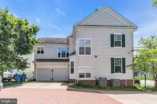 10079 Orland Stone Dr, Bristow, VA 20136 - back of property with decorative driveway, a garage, central AC unit, a standing seam roof, and metal roof