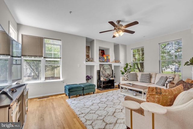 10079 Orland Stone Dr, Bristow, VA 20136 - living area with light wood-style floors, ceiling fan, baseboards, and a fireplace with flush hearth