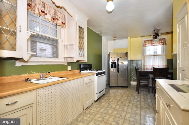 3324 Ryan Ave, Philadelphia, PA 19136 - kitchen with white gas range, stainless steel fridge, a sink, light countertops, and glass insert cabinets