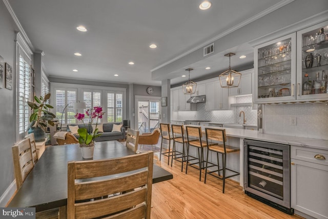 3805 Warren St NW, Washington, DC 20016 - dining space with wine cooler, crown molding, recessed lighting, light wood-style flooring, and bar area