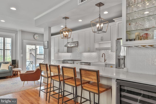 3805 Warren St NW, Washington, DC 20016 - kitchen featuring wine cooler, under cabinet range hood, a sink, a kitchen breakfast bar, and light wood finished floors