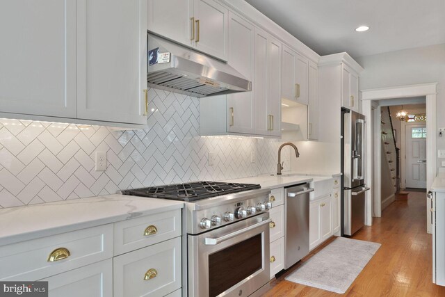 3805 Warren St NW, Washington, DC 20016 - kitchen with high end appliances, under cabinet range hood, a sink, white cabinetry, and backsplash
