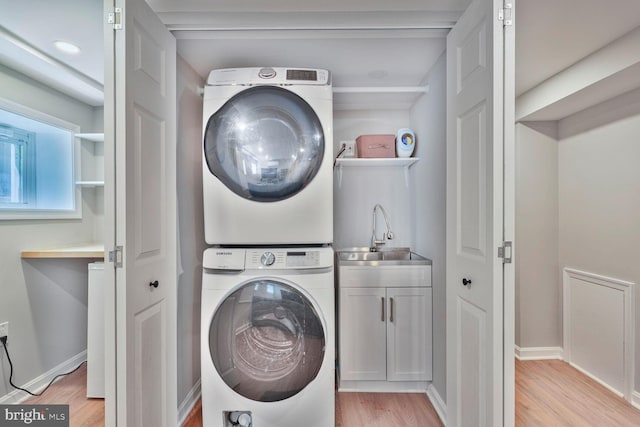 3805 Warren St NW, Washington, DC 20016 - washroom featuring estacked washer and dryer, cabinet space, light wood-style flooring, and baseboards