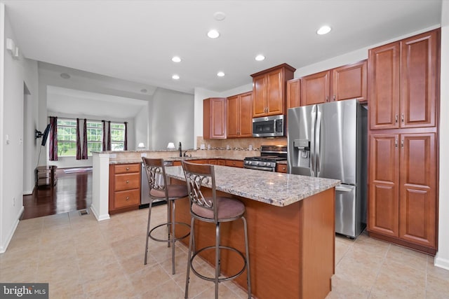 133 E General Grey Ct, Newark, DE 19702 - kitchen with stainless steel appliances, a peninsula, light stone countertops, recessed lighting, and brown cabinets