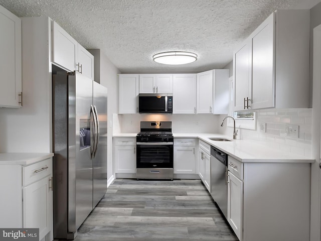 86 Summerfield Dr, Annapolis, MD 21403 - kitchen with appliances with stainless steel finishes, a sink, light wood-style flooring, white cabinetry, and a textured ceiling