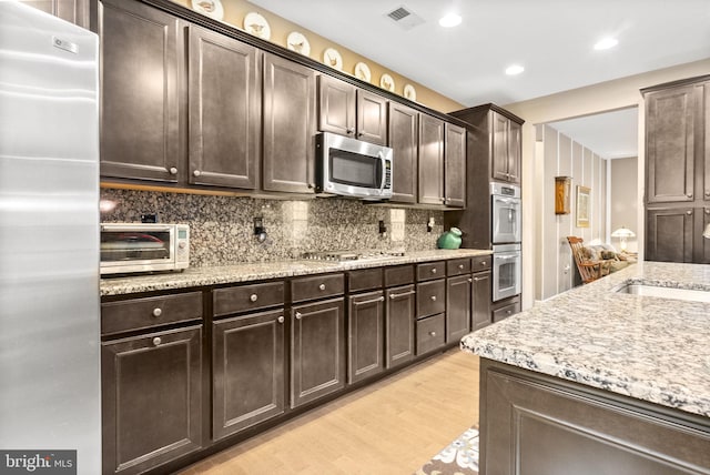 220 Wilshire Blvd, Woolwich Twp, NJ 08085 - kitchen with appliances with stainless steel finishes, dark brown cabinets, backsplash, light wood-style floors, and light stone counters