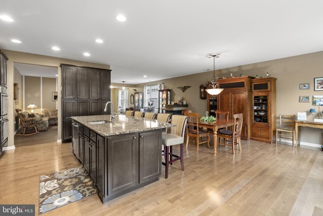 220 Wilshire Blvd, Woolwich Twp, NJ 08085 - kitchen featuring a sink, light wood-style flooring, a breakfast bar, a kitchen island with sink, and dark brown cabinetry