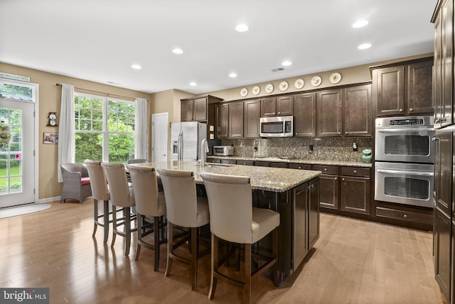 220 Wilshire Blvd, Woolwich Twp, NJ 08085 - kitchen with stainless steel appliances, dark brown cabinetry, a kitchen breakfast bar, a kitchen island with sink, and light wood finished floors