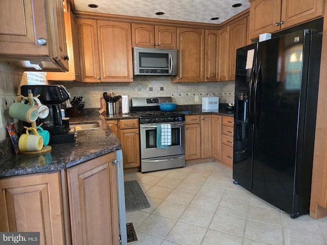 354 Rupert Ct, Millersville, MD 21108 - kitchen featuring appliances with stainless steel finishes, tasteful backsplash, light tile patterned floors, brown cabinetry, and dark stone counters