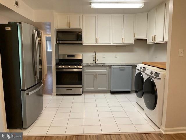 8485 Greenbelt Rd Unit 8485-T-1, Greenbelt, MD 20770 - kitchen featuring appliances with stainless steel finishes, a sink, washer and dryer, light countertops, and light tile patterned floors