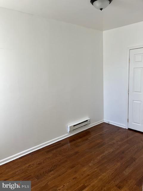 1910 Mcclellan St, Philadelphia, PA 19145 - unfurnished room featuring a baseboard heating unit, dark wood-type flooring, and baseboards