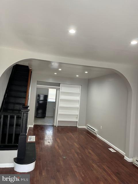 1910 Mcclellan St, Philadelphia, PA 19145 - unfurnished living room with a baseboard radiator, arched walkways, wood finished floors, recessed lighting, and baseboards