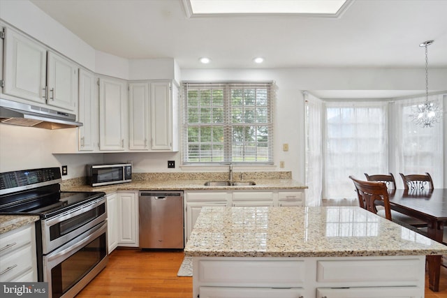 3663 Thomasson Crossing Dr, Triangle, VA 22172 - kitchen with stainless steel appliances, under cabinet range hood, light wood-type flooring, a kitchen island, and white cabinetry