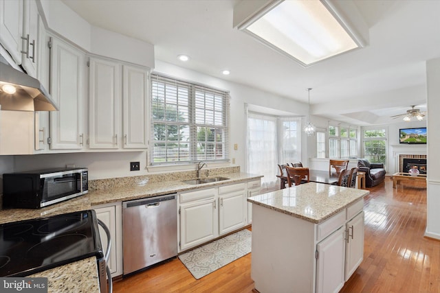 3663 Thomasson Crossing Dr, Triangle, VA 22172 - kitchen with stainless steel appliances, a center island, white cabinetry, a brick fireplace, and recessed lighting
