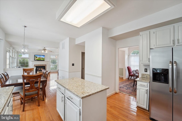 3663 Thomasson Crossing Dr, Triangle, VA 22172 - kitchen with stainless steel fridge, a fireplace, light wood-style floors, a center island, and light stone countertops
