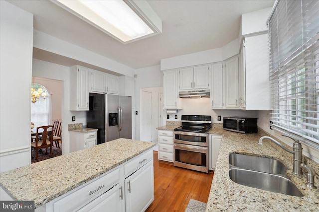 3663 Thomasson Crossing Dr, Triangle, VA 22172 - kitchen featuring stainless steel appliances, under cabinet range hood, white cabinets, light wood-style floors, and a center island