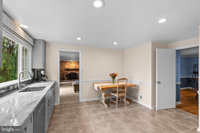 9824 Whetstone Dr, Montgomery Village, MD 20886 - kitchen with gray cabinets, a sink, stainless steel dishwasher, a brick fireplace, and light stone countertops