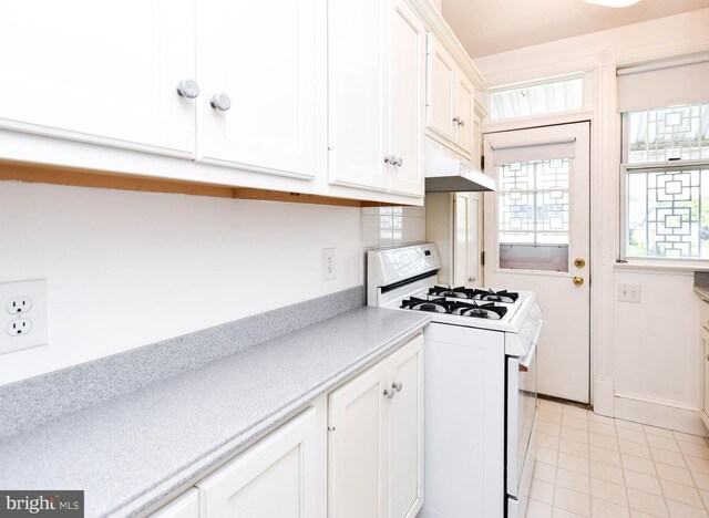 1432 C St SE, Washington, DC 20003 - kitchen with white gas range, white cabinetry, light countertops, under cabinet range hood, and light tile patterned floors