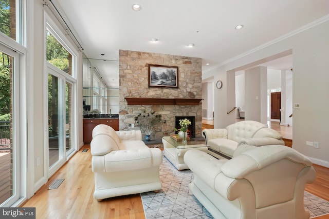 12213 Lake Potomac Ter, Potomac, MD 20854 - living room featuring light wood-style flooring, crown molding, stairs, baseboards, and a stone fireplace